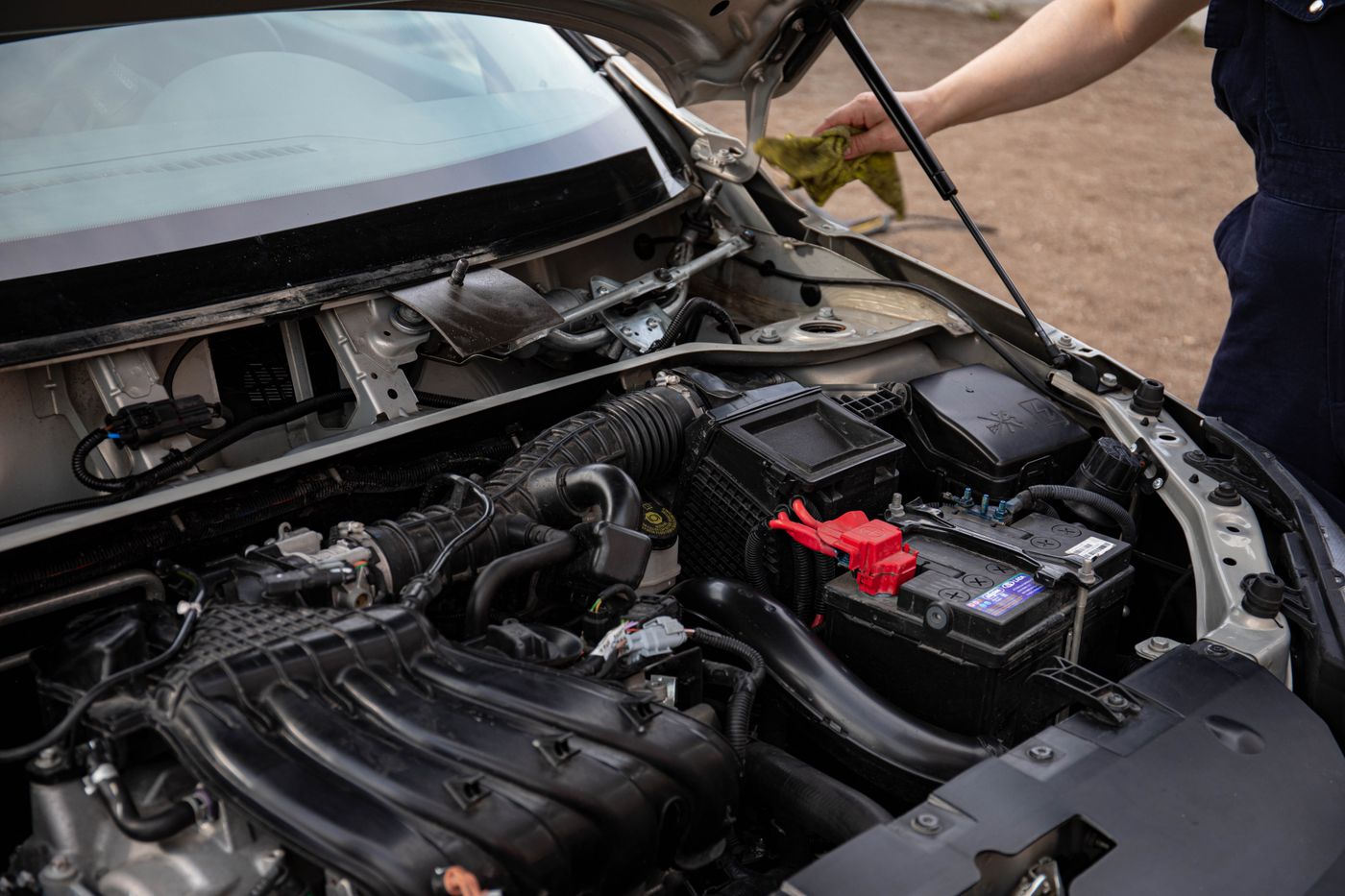 Technician servicing an engine bay and battery