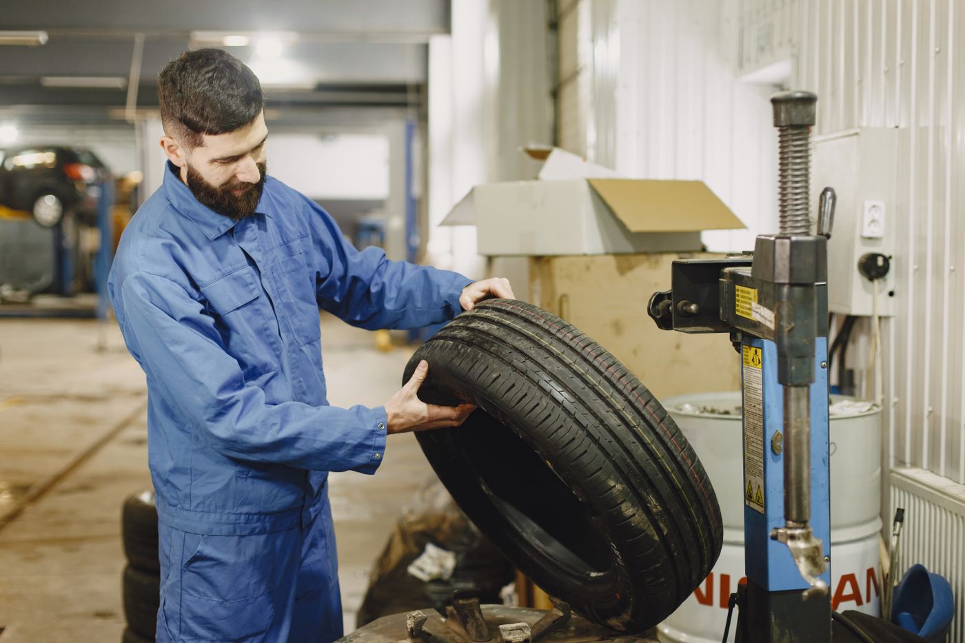 Technician holding a tire beside the wheel-mounting machine