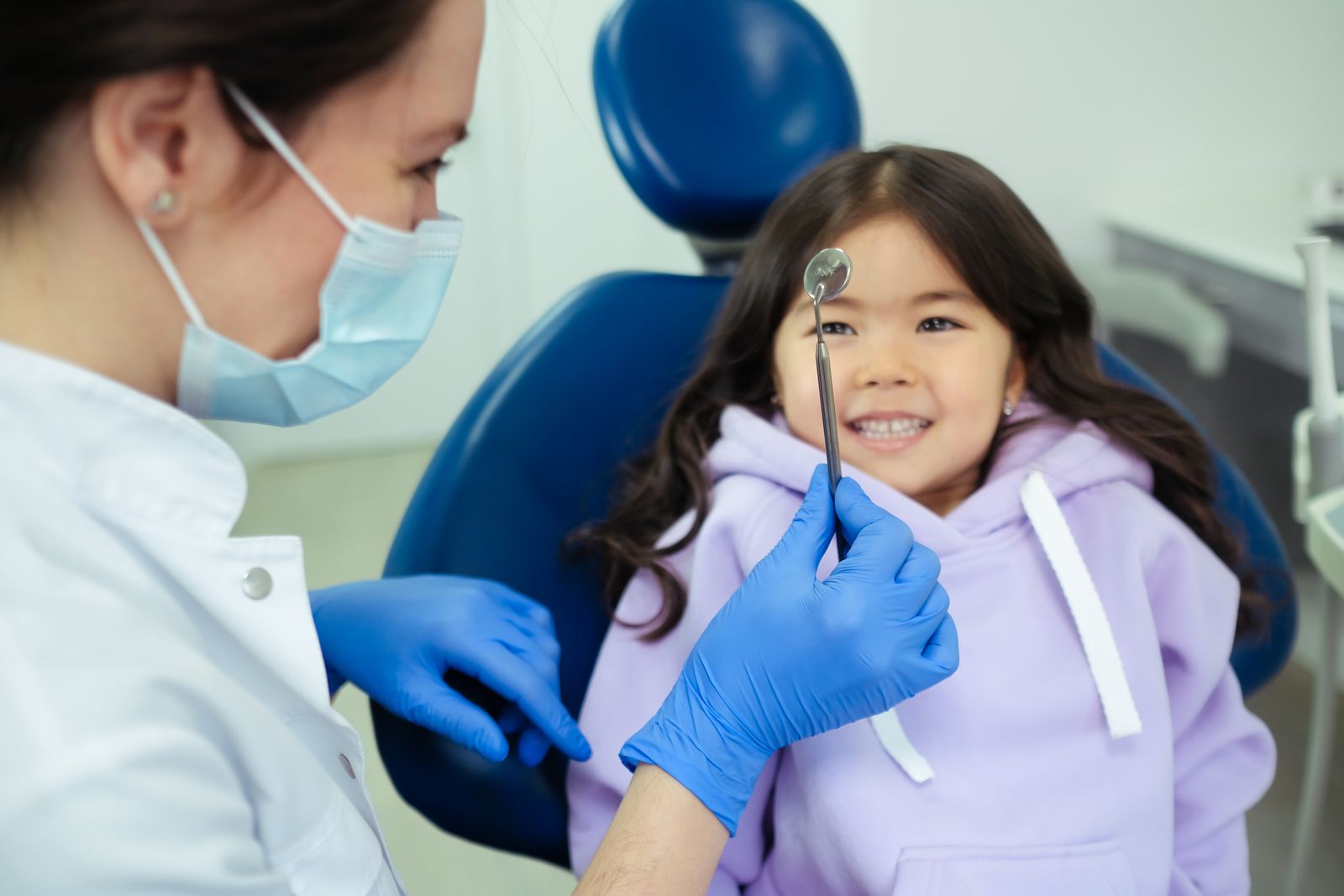 A dentist making a young child smile during a gentle checkup