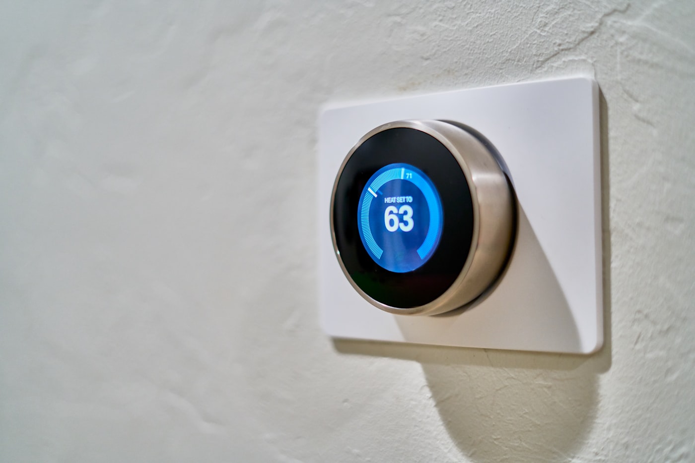 Smart thermostat mounted on a wall showing set temperature