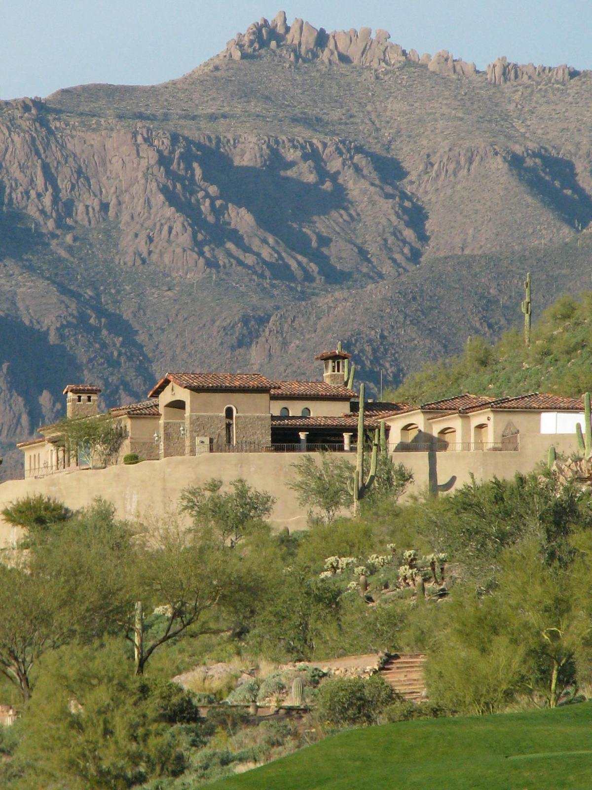 Mediterranean hillside villa beneath rugged desert mountains and saguaros